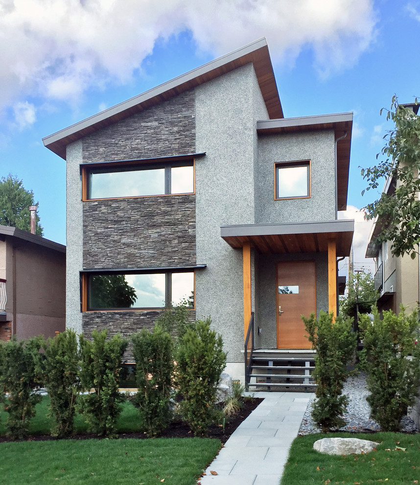 Imagen de fachada de casa gris contemporánea de tamaño medio de dos plantas con revestimientos combinados y tejado de teja de madera