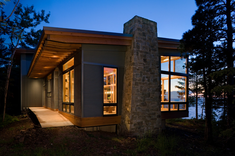 На фото: маленький, двухэтажный дом в стиле модернизм с облицовкой из металла для на участке и в саду, охотников с