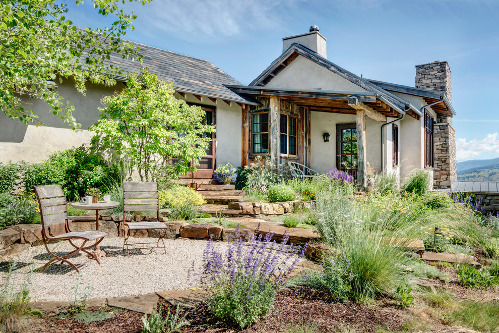 Idée de décoration pour une grande façade de maison beige chalet en stuc de plain-pied.