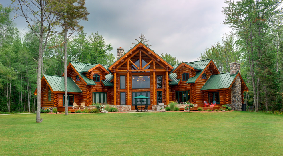На фото: большой, двухэтажный, деревянный, коричневый частный загородный дом в стиле рустика с двускатной крышей и металлической крышей