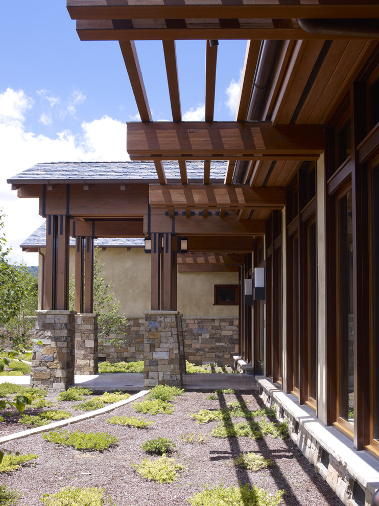 Imagen de fachada de casa beige actual grande de una planta con revestimientos combinados, tejado plano y tejado de varios materiales