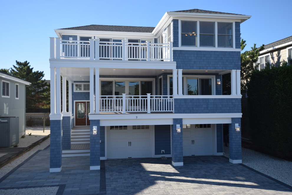 Large beach style blue three-story wood house exterior photo in Philadelphia with a hip roof and a shingle roof