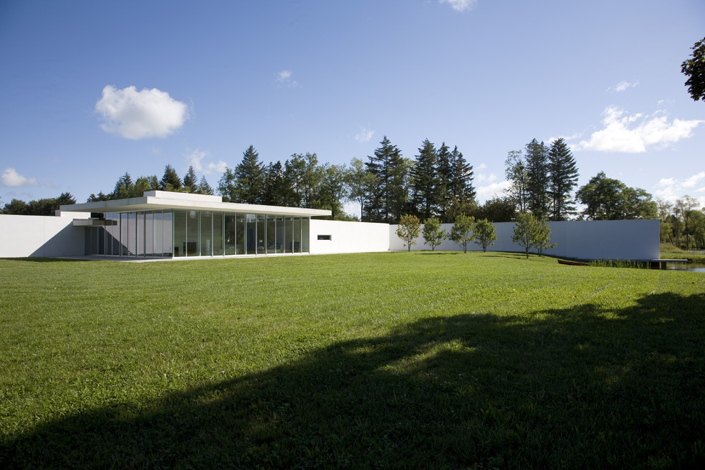 Ejemplo de fachada de casa blanca minimalista de una planta con revestimiento de estuco y tejado plano