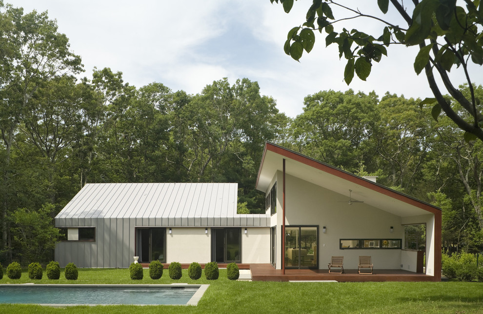 Medium sized and beige contemporary bungalow house exterior in New York with metal cladding and a lean-to roof.