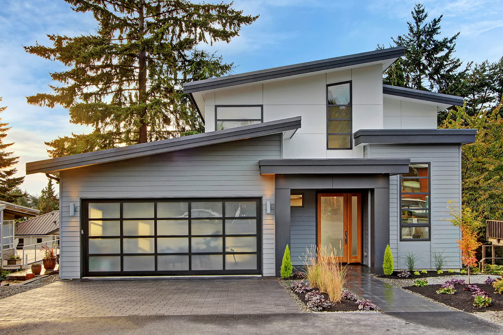 Idée de décoration pour une grande façade de maison grise design en bois à un étage avec un toit plat.