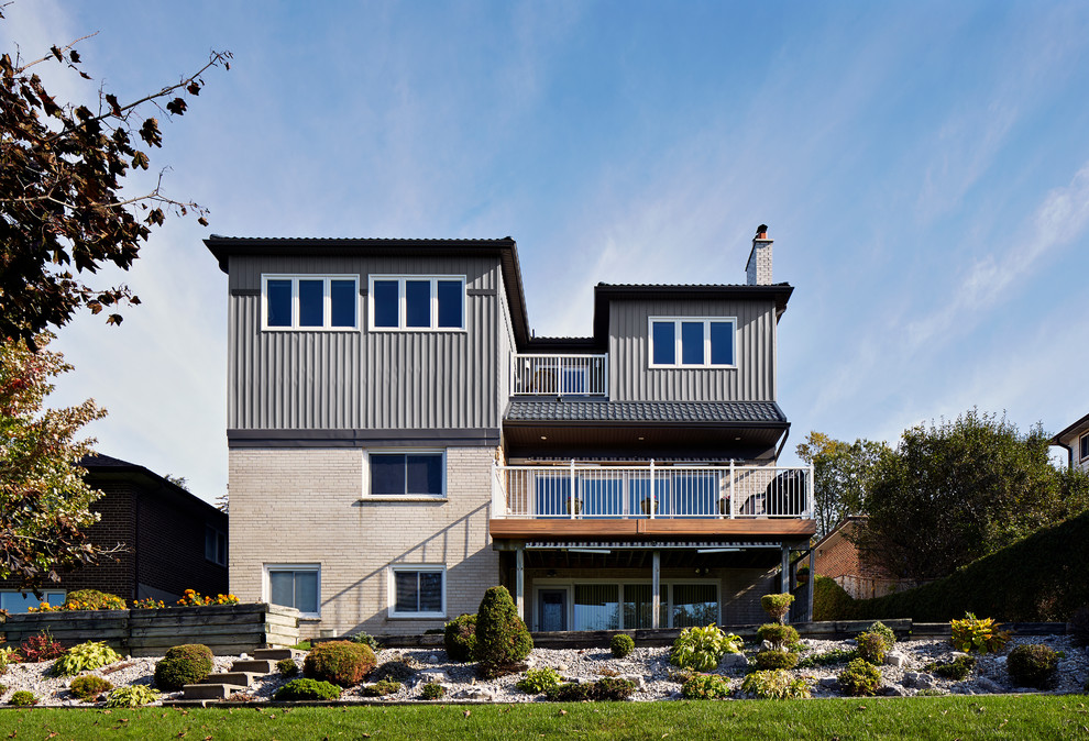 Diseño de fachada de casa actual de tres plantas con revestimientos combinados y tejado de teja de barro
