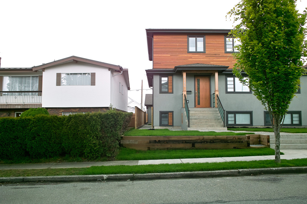 This is an example of a medium sized and gey contemporary two floor render house exterior in Vancouver.