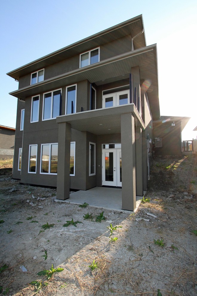 Cette photo montre une façade de maison grise éclectique en stuc à un étage.