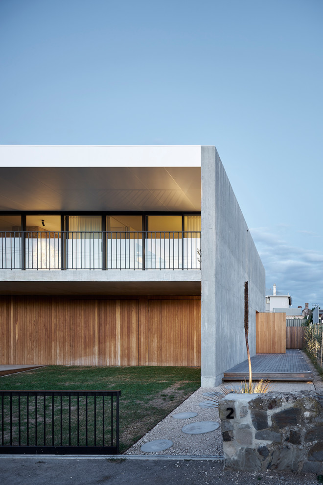Cette image montre une façade de maison grise vintage à un étage avec un revêtement mixte et un toit plat.