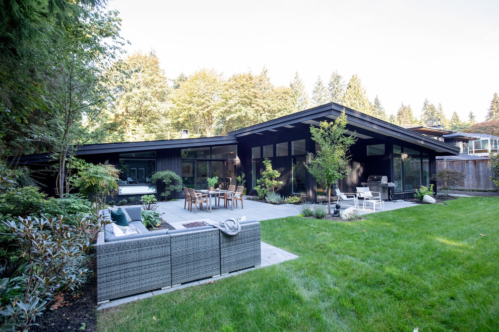 Example of a mid-sized mid-century modern black one-story wood house exterior design in Vancouver with a shed roof and a shingle roof