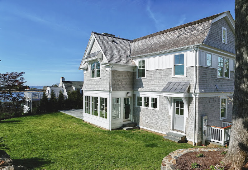 This is an example of a large and gey coastal two floor detached house in New York with wood cladding, a hip roof and a shingle roof.