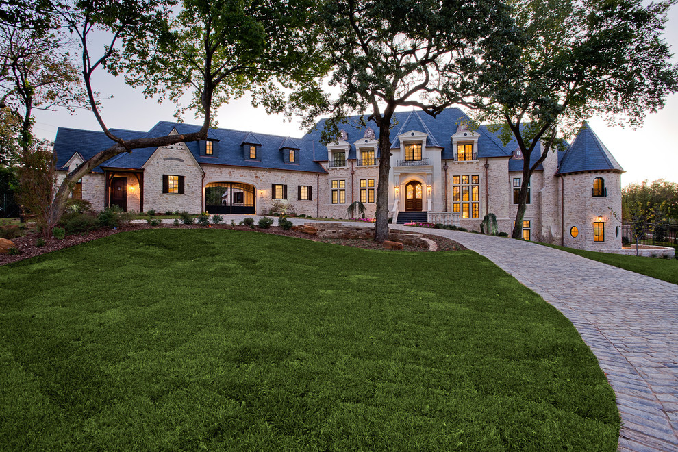 Example of a huge ornate beige three-story stone house exterior design in Dallas with a hip roof and a tile roof