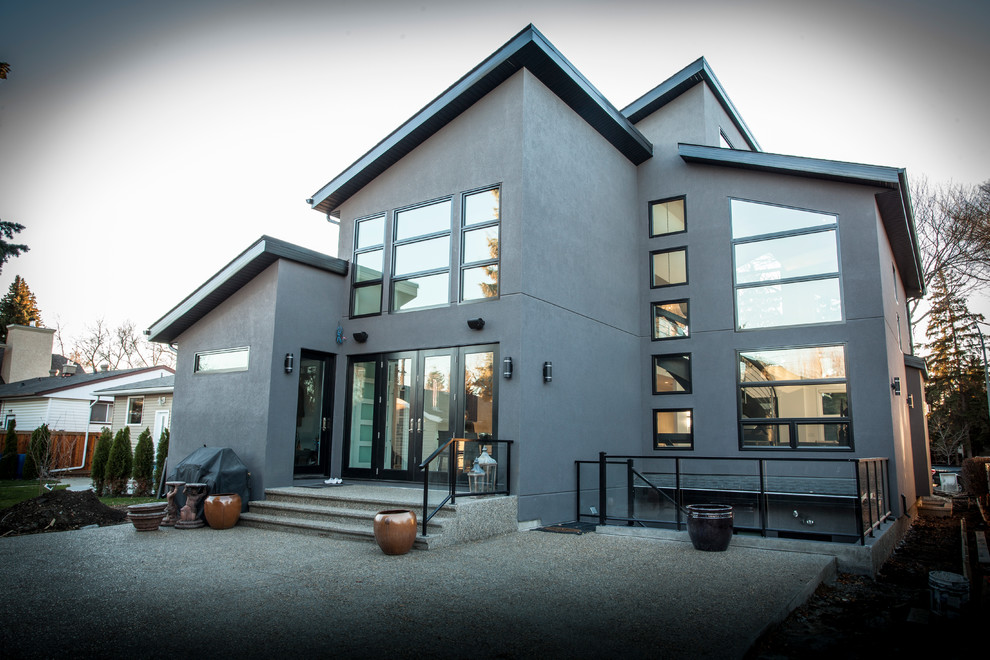 Inspiration pour une façade de maison grise minimaliste en stuc à un étage avec un toit en appentis.