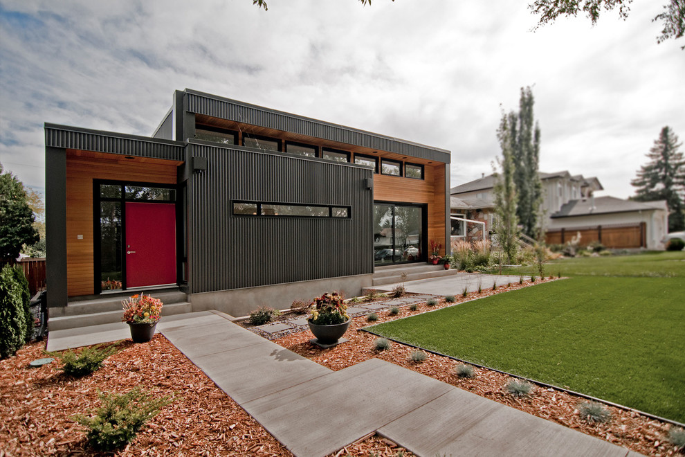 Стильный дизайн: одноэтажный, черный дом среднего размера в стиле модернизм с плоской крышей и облицовкой из металла - последний тренд