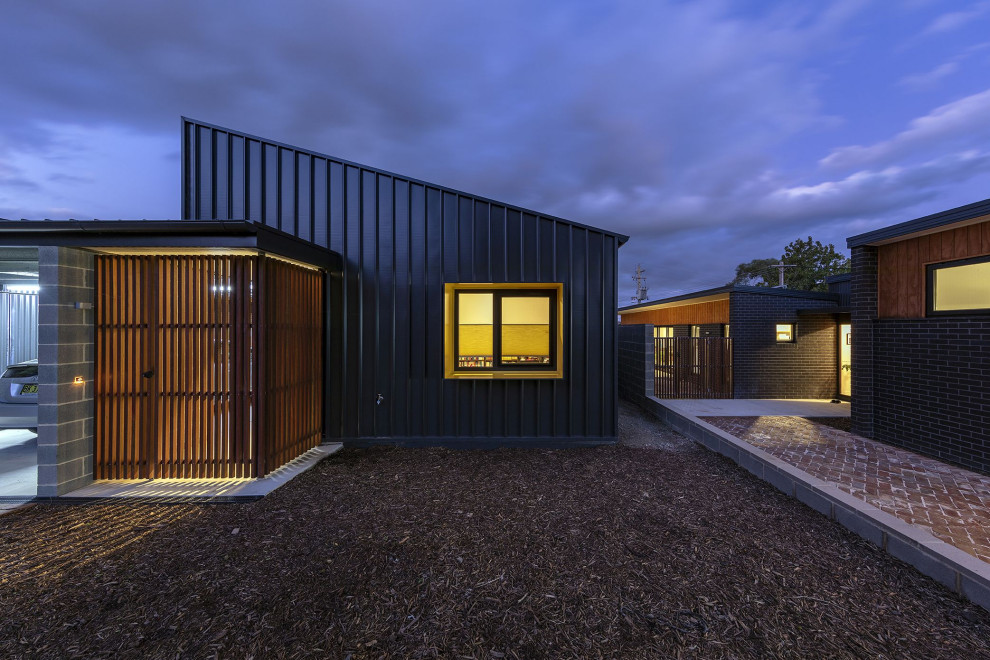 Идея дизайна: маленький, одноэтажный частный загородный дом в современном стиле с комбинированной облицовкой и металлической крышей для на участке и в саду