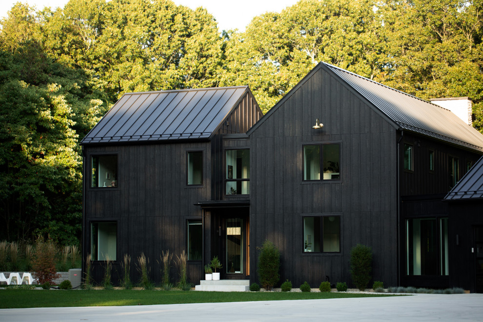 Idées déco pour une façade de maison noire contemporaine en bois et planches et couvre-joints à un étage avec un toit à deux pans, un toit en métal et un toit gris.