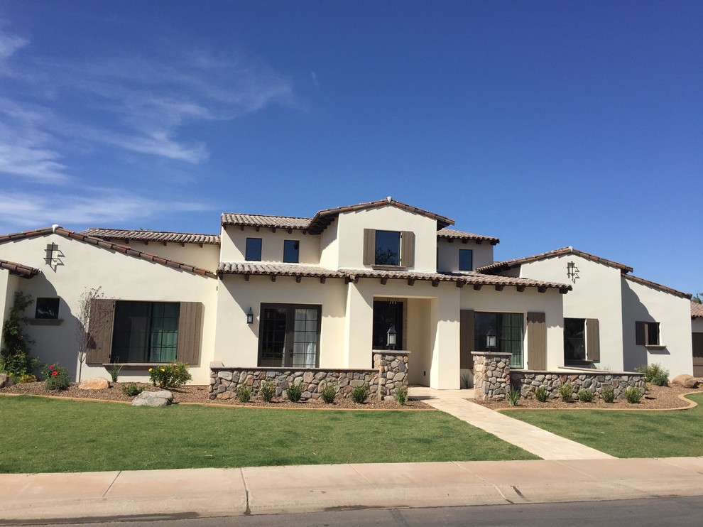 Large southwest beige two-story stucco exterior home photo in Phoenix with a shingle roof