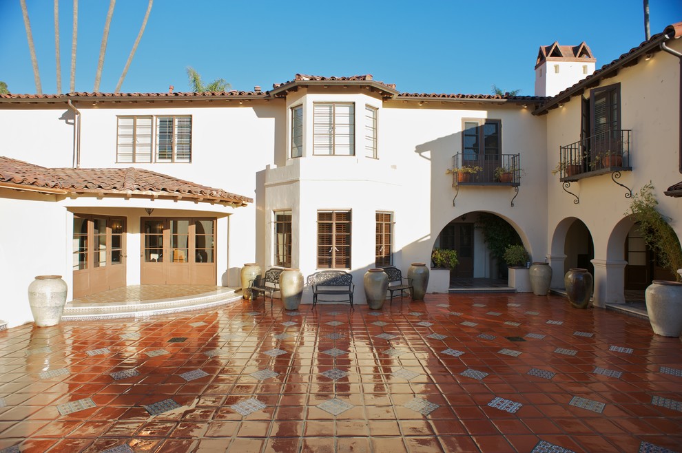 Cette photo montre une grande façade de maison beige méditerranéenne en stuc à un étage.