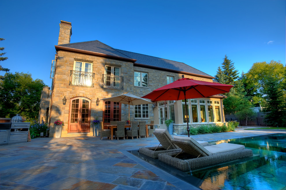 This is an example of a medium sized mediterranean house exterior in Calgary with stone cladding.