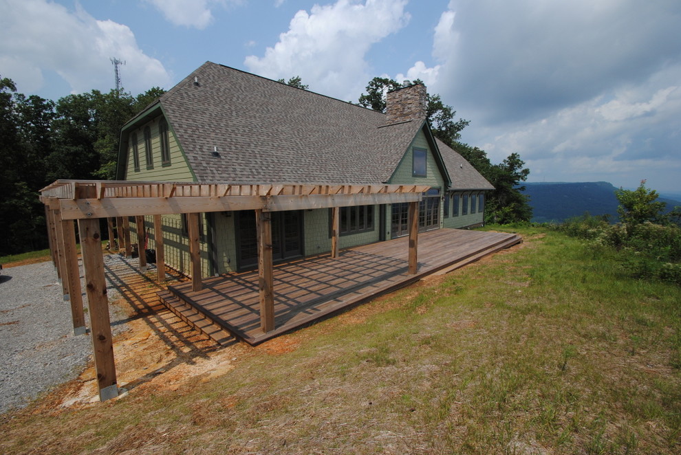 Esempio della villa grande verde country a due piani con rivestimento con lastre in cemento, falda a timpano, copertura a scandole, tetto marrone e pannelli sovrapposti