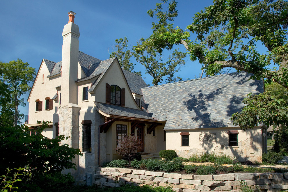 На фото: большой, двухэтажный, бежевый дом в классическом стиле с облицовкой из камня и двускатной крышей