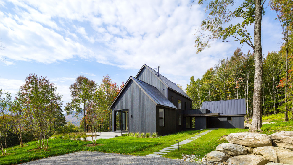 Idée de décoration pour une façade de maison noire champêtre avec un toit à deux pans, un toit en métal et un toit noir.