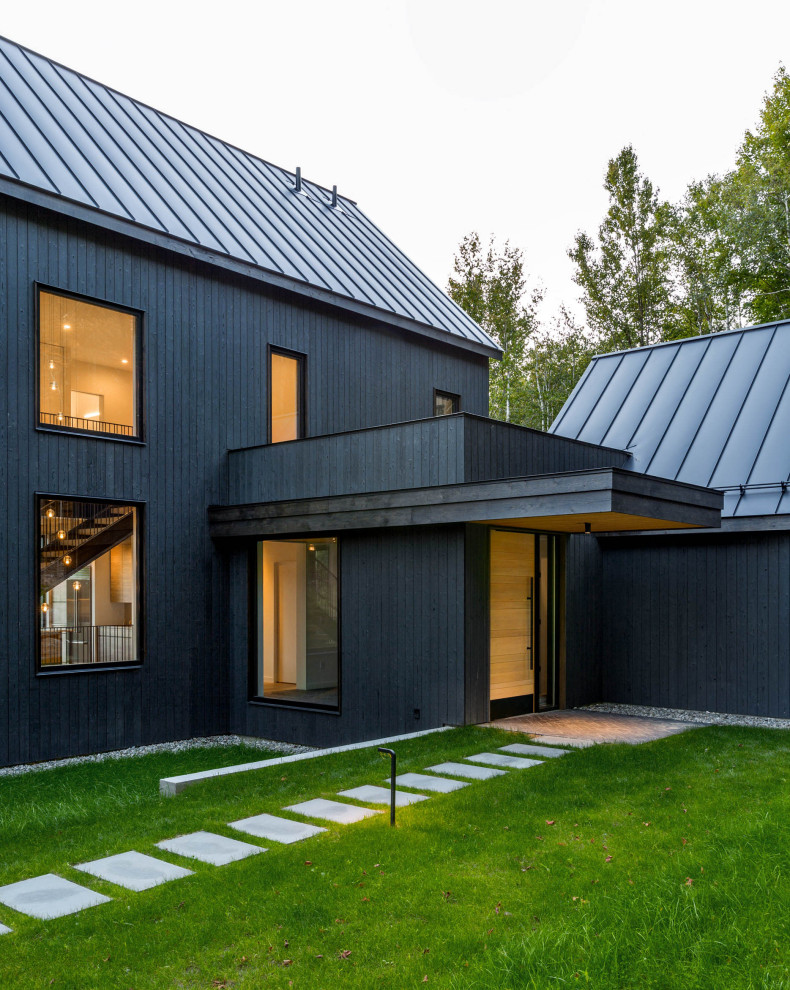 Cette photo montre une grande façade de maison noire moderne en bois à deux étages et plus.