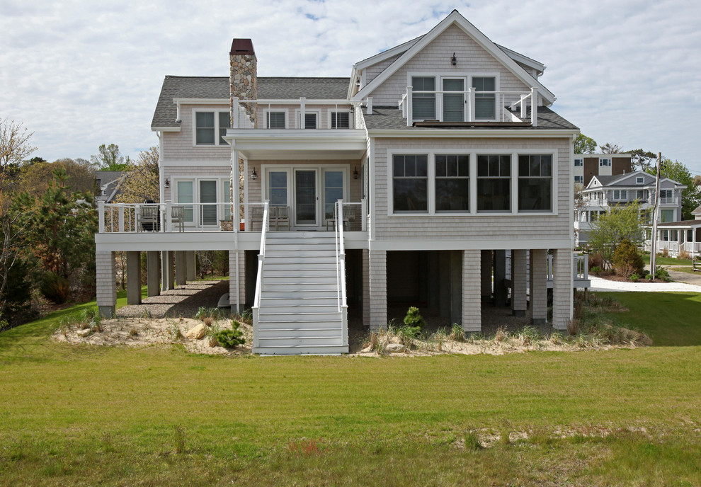 Photo of a white coastal two floor house exterior in Boston with wood cladding and a pitched roof.