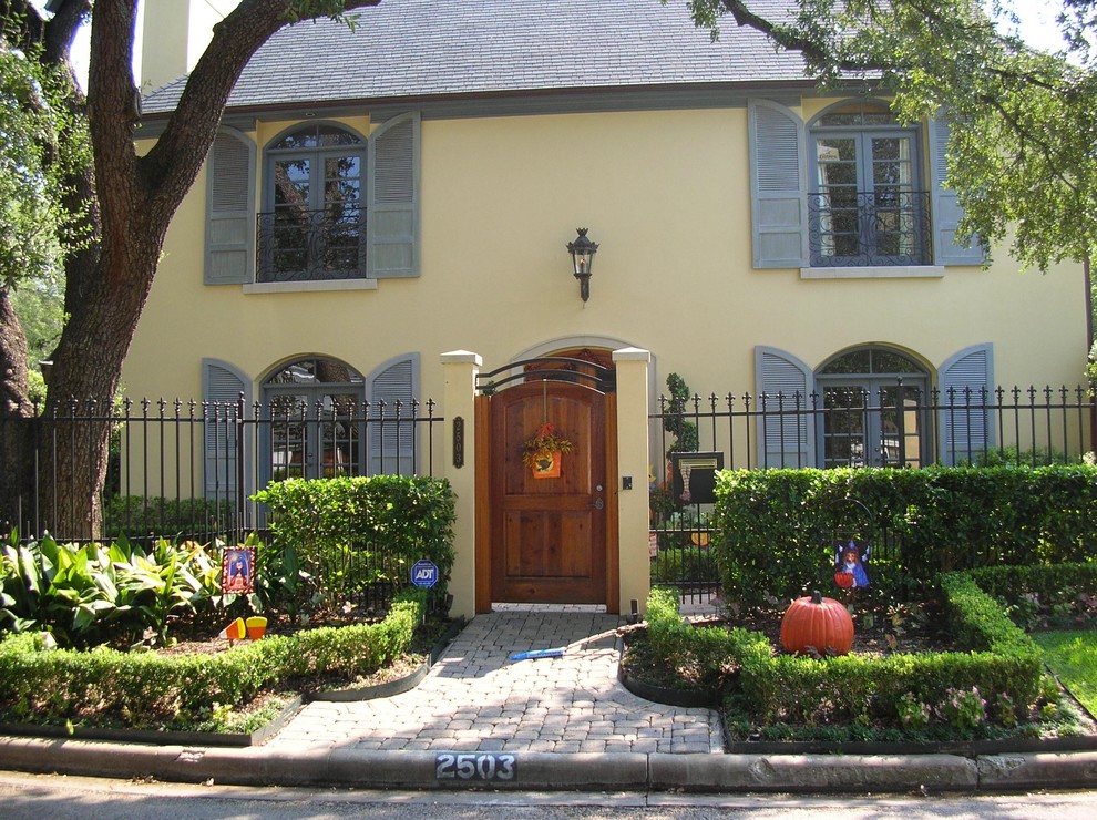 Mid-sized mediterranean yellow two-story stucco exterior home idea in Houston with a hip roof