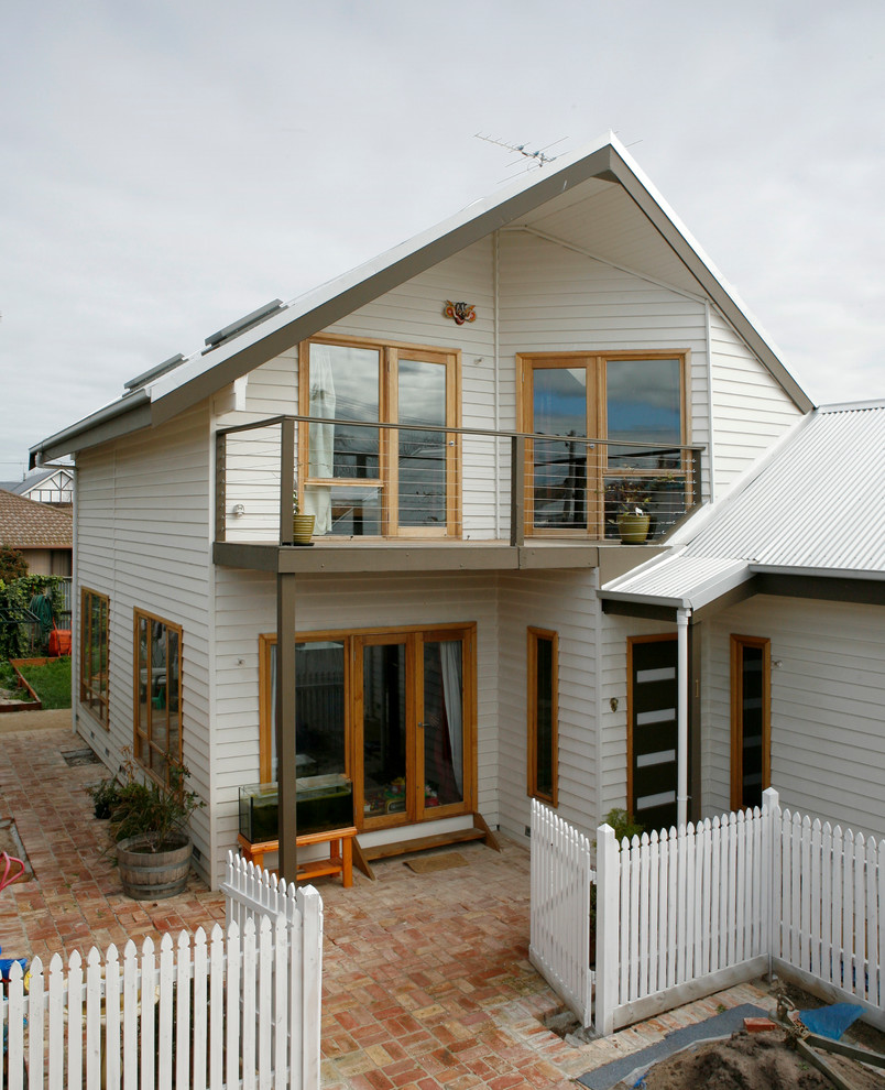 Inspiration for a medium sized and white modern two floor house exterior in Melbourne with wood cladding and a hip roof.