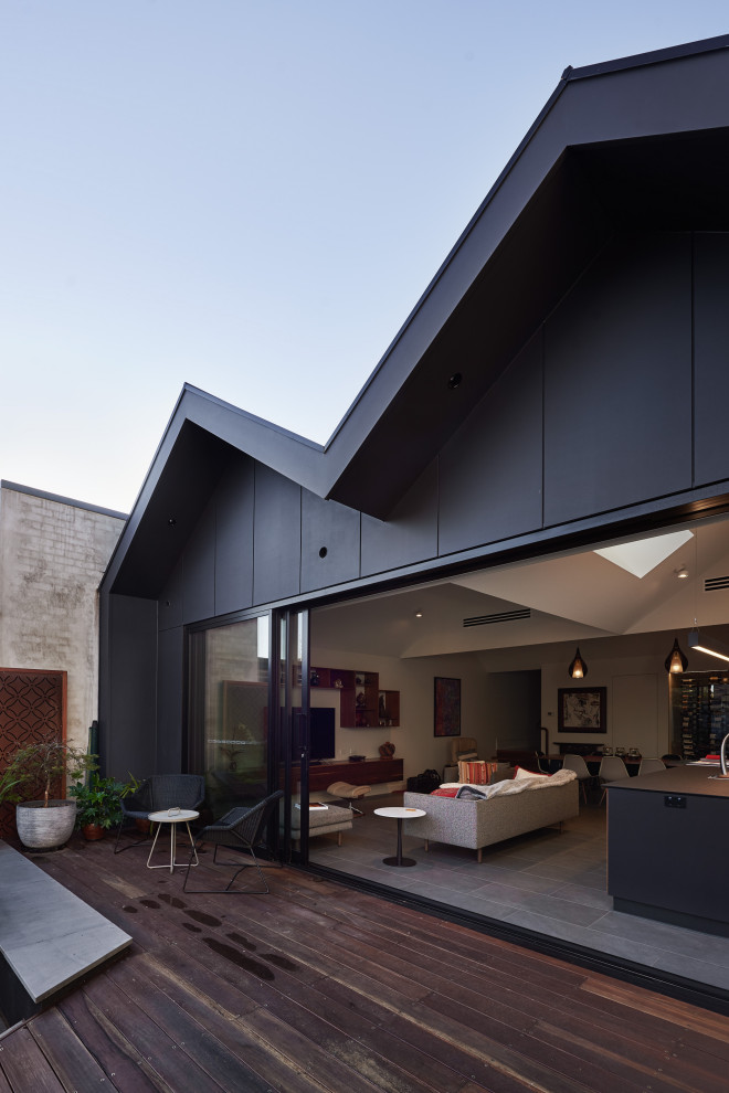 Идея дизайна: двухэтажный, черный частный загородный дом среднего размера в современном стиле с облицовкой из металла, двускатной крышей и металлической крышей