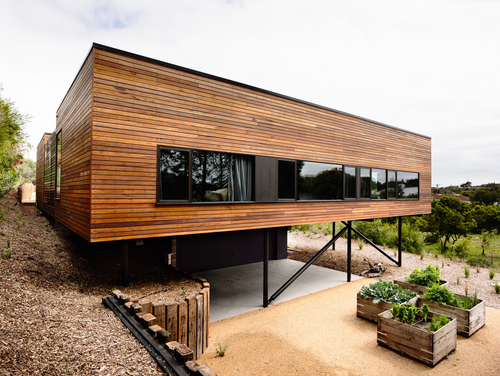 Cette image montre une façade de maison marron design en bois de taille moyenne avec un toit plat.