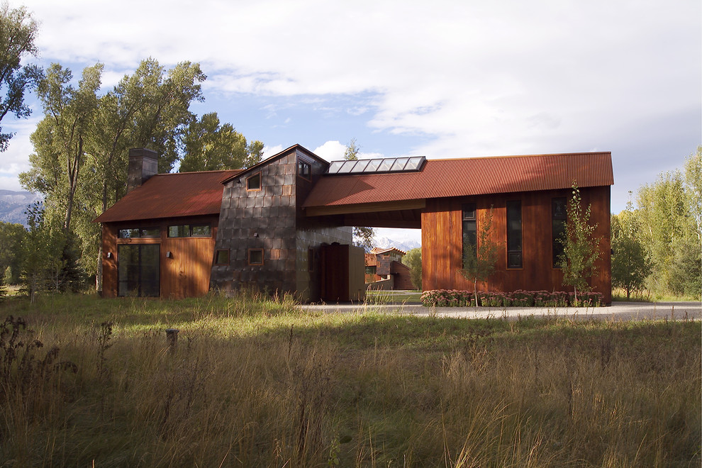 На фото: большой, двухэтажный, коричневый частный загородный дом в стиле рустика с комбинированной облицовкой и металлической крышей с