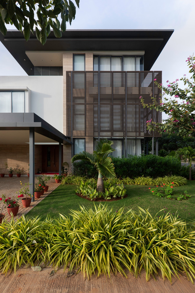 Inspiration for a multi-coloured contemporary detached house in Bengaluru with three floors, mixed cladding and a flat roof.