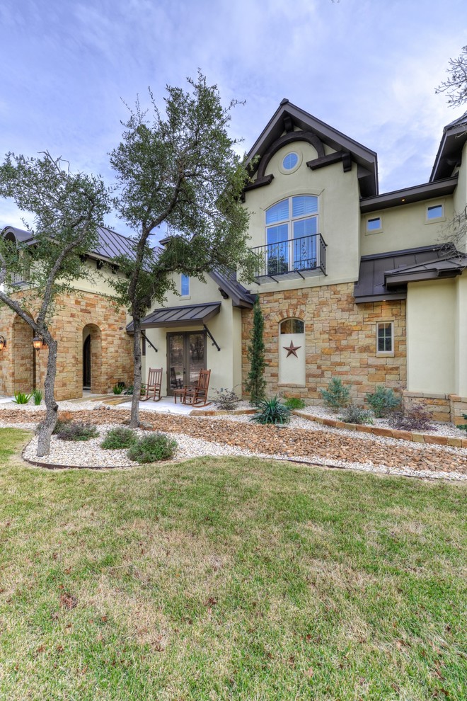 Example of a large transitional beige one-story stucco exterior home design in Austin