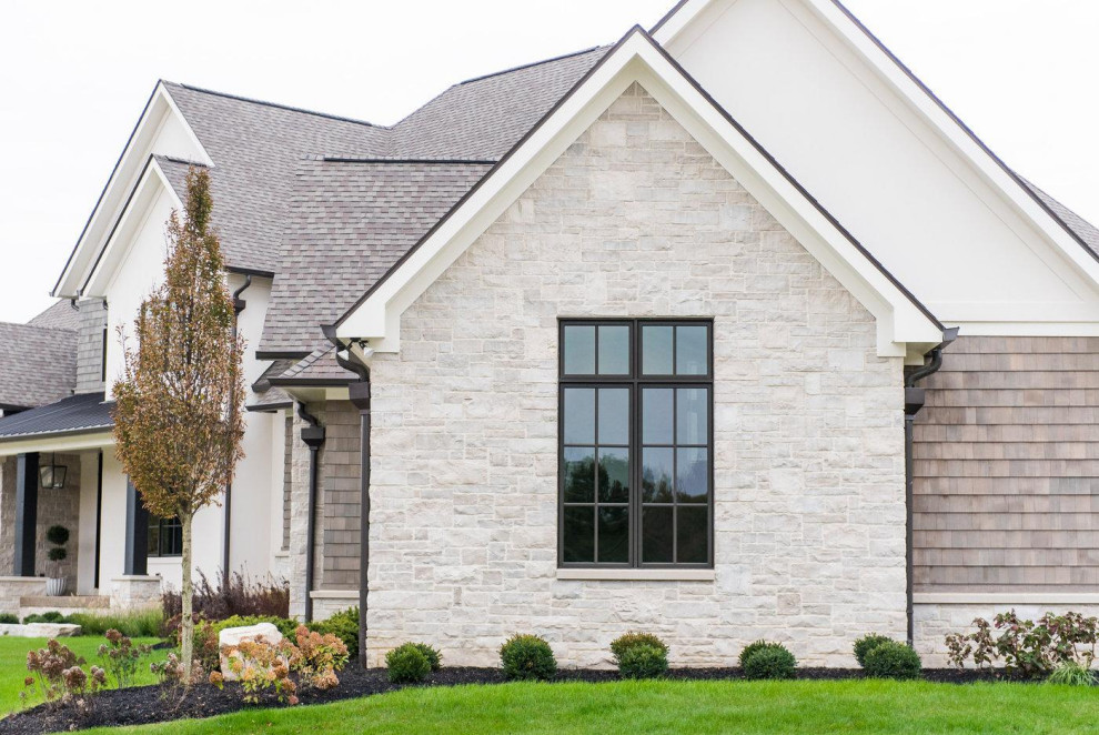 Large traditional gray two-story stone house exterior idea in Other with a shingle roof