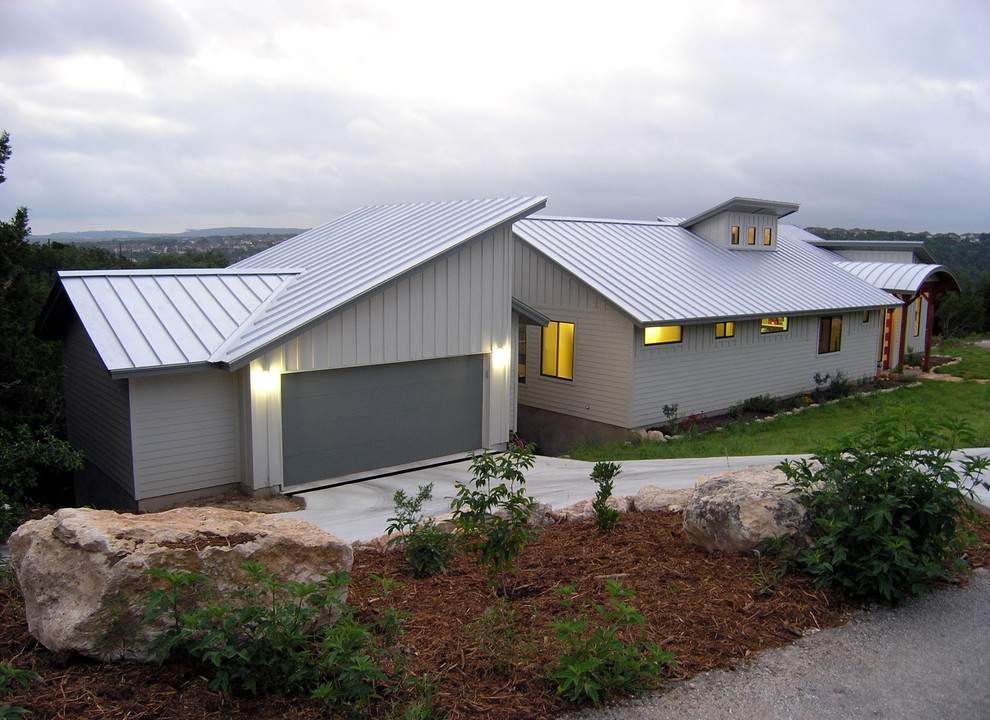 Cette image montre une petite façade de maison blanche design en bois de plain-pied avec un toit en métal.