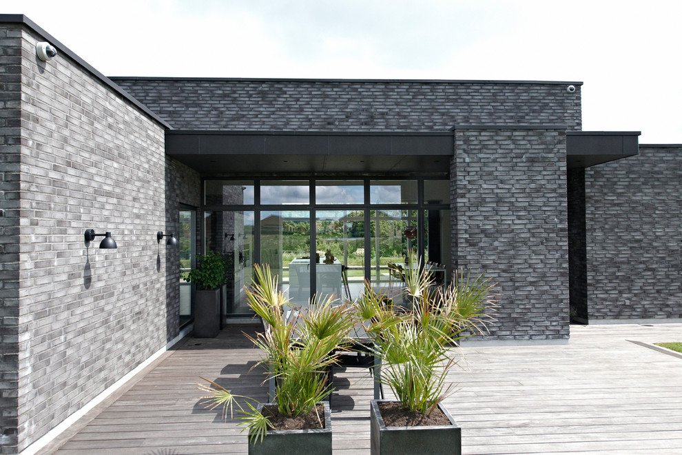Diseño de fachada gris contemporánea de tamaño medio de una planta con revestimiento de ladrillo y tejado plano