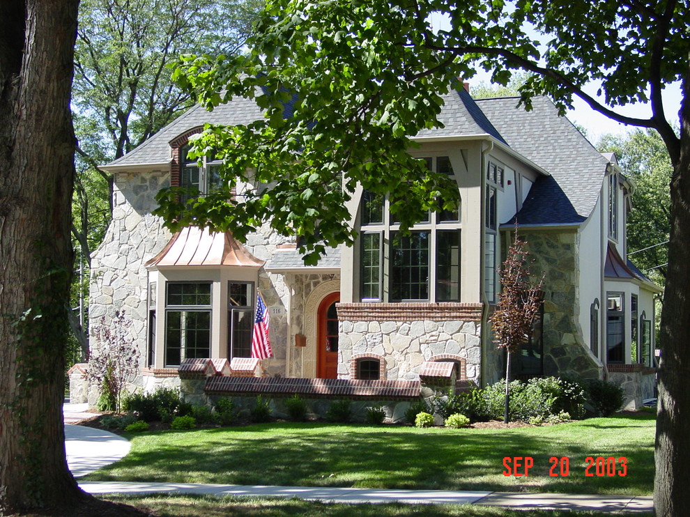 Example of a mid-sized classic beige two-story stone house exterior design in Chicago with a hip roof and a shingle roof