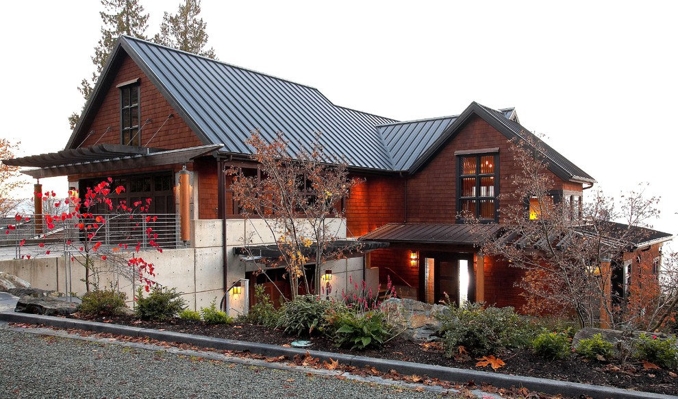 Foto de fachada de casa marrón moderna grande de tres plantas con revestimiento de madera, tejado a dos aguas y tejado de metal