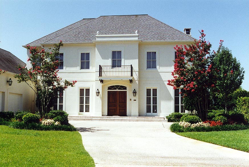 Inspiration for a large timeless beige two-story stucco house exterior remodel in New Orleans with a hip roof and a shingle roof