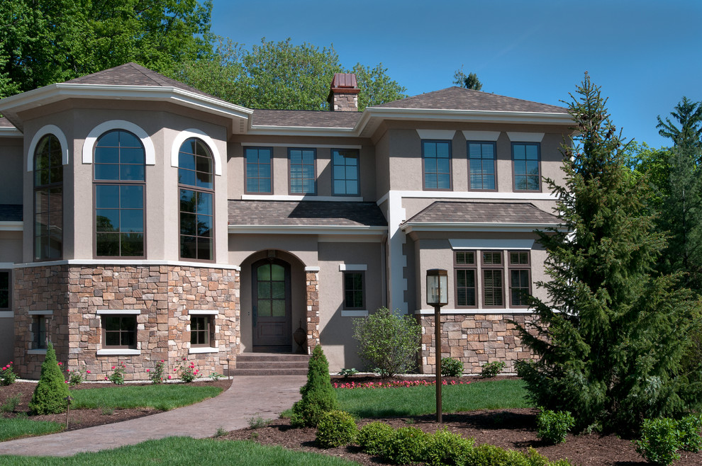 Example of a large tuscan brown three-story stucco exterior home design in Grand Rapids with a hip roof