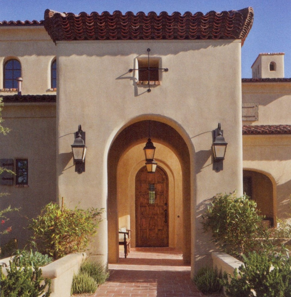 This is an example of a large and beige mediterranean two floor house exterior in Phoenix.