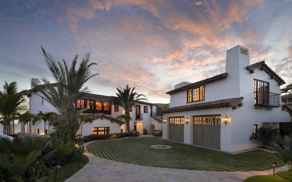 На фото: большой, двухэтажный, белый дом в средиземноморском стиле с облицовкой из цементной штукатурки и двускатной крышей с
