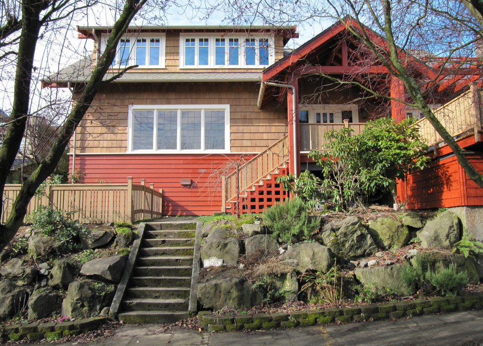 Idee per la facciata di una casa rossa american style a due piani di medie dimensioni con rivestimenti misti, tetto a capanna e terreno in pendenza