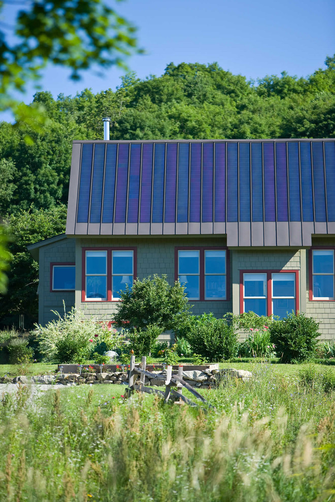 Inspiration pour une façade de maison verte chalet en bois de taille moyenne et de plain-pied avec un toit à quatre pans, un toit en métal et un toit bleu.
