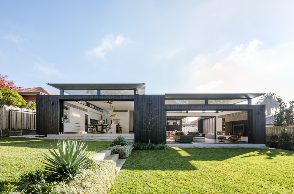 Immagine della villa nera contemporanea a un piano di medie dimensioni con rivestimento in legno, copertura in metallo o lamiera e tetto piano