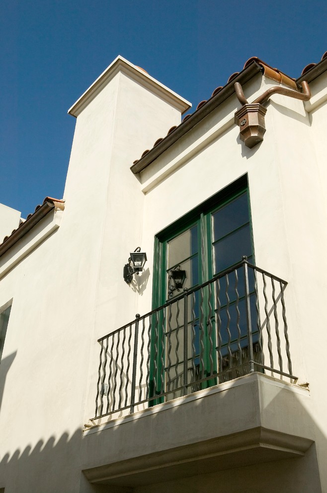 На фото: маленький, трехэтажный, белый дом в средиземноморском стиле с облицовкой из цементной штукатурки для на участке и в саду