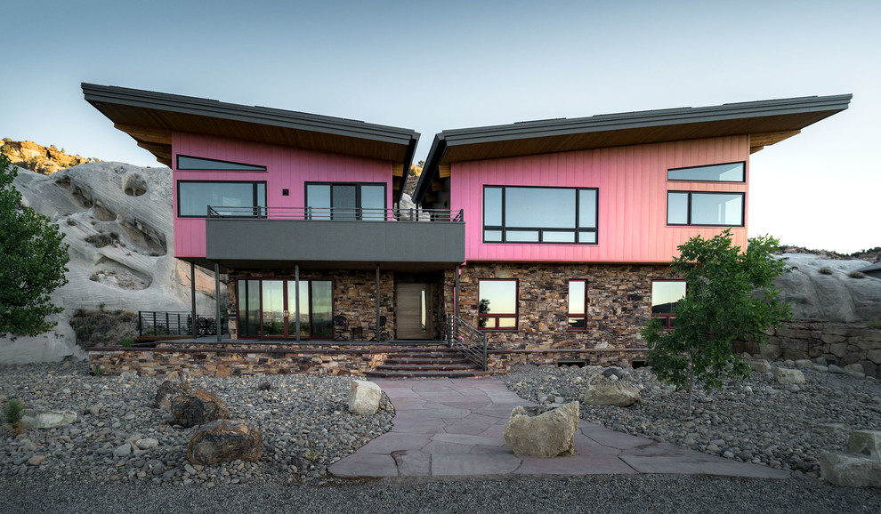 Ejemplo de fachada de casa rosa contemporánea de dos plantas con revestimientos combinados y tejado de un solo tendido