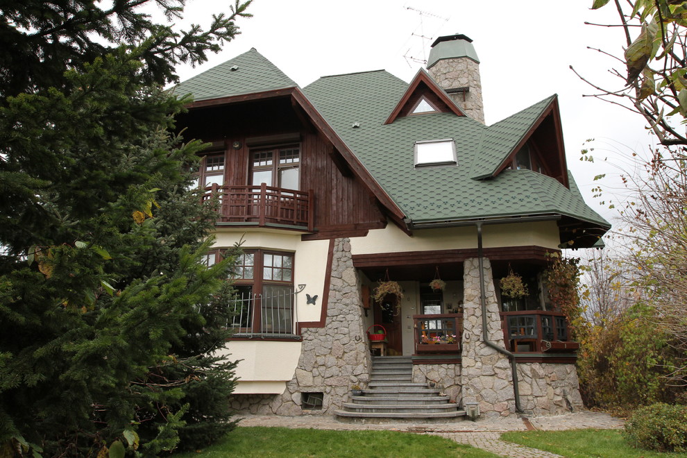 Immagine della facciata di una casa country a due piani con rivestimenti misti e copertura a scandole